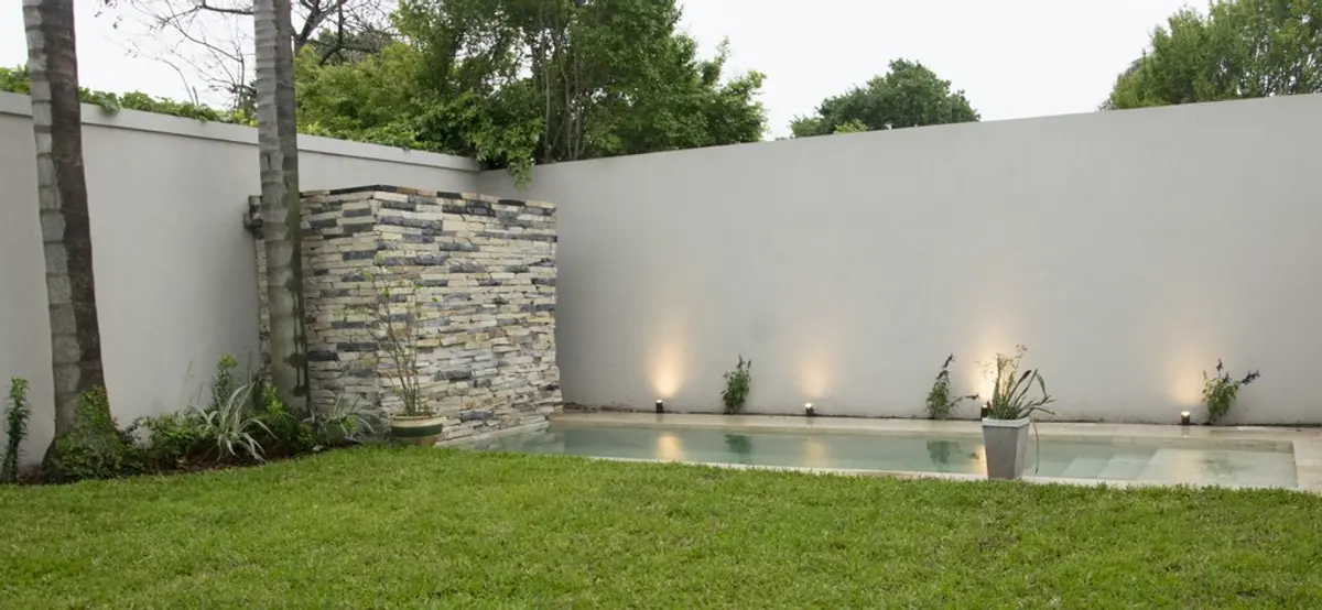 Patio moderno con piscina, pared de piedra y césped — proyecto Casa Estilo Francés, por Estudio Fernandez Long & asoc., en Martínez