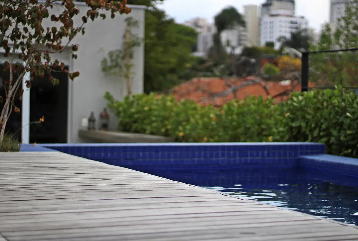 Pileta moderna con deck de madera y jardines verdes al fondo — proyecto Residência HC, por Gil Fialho