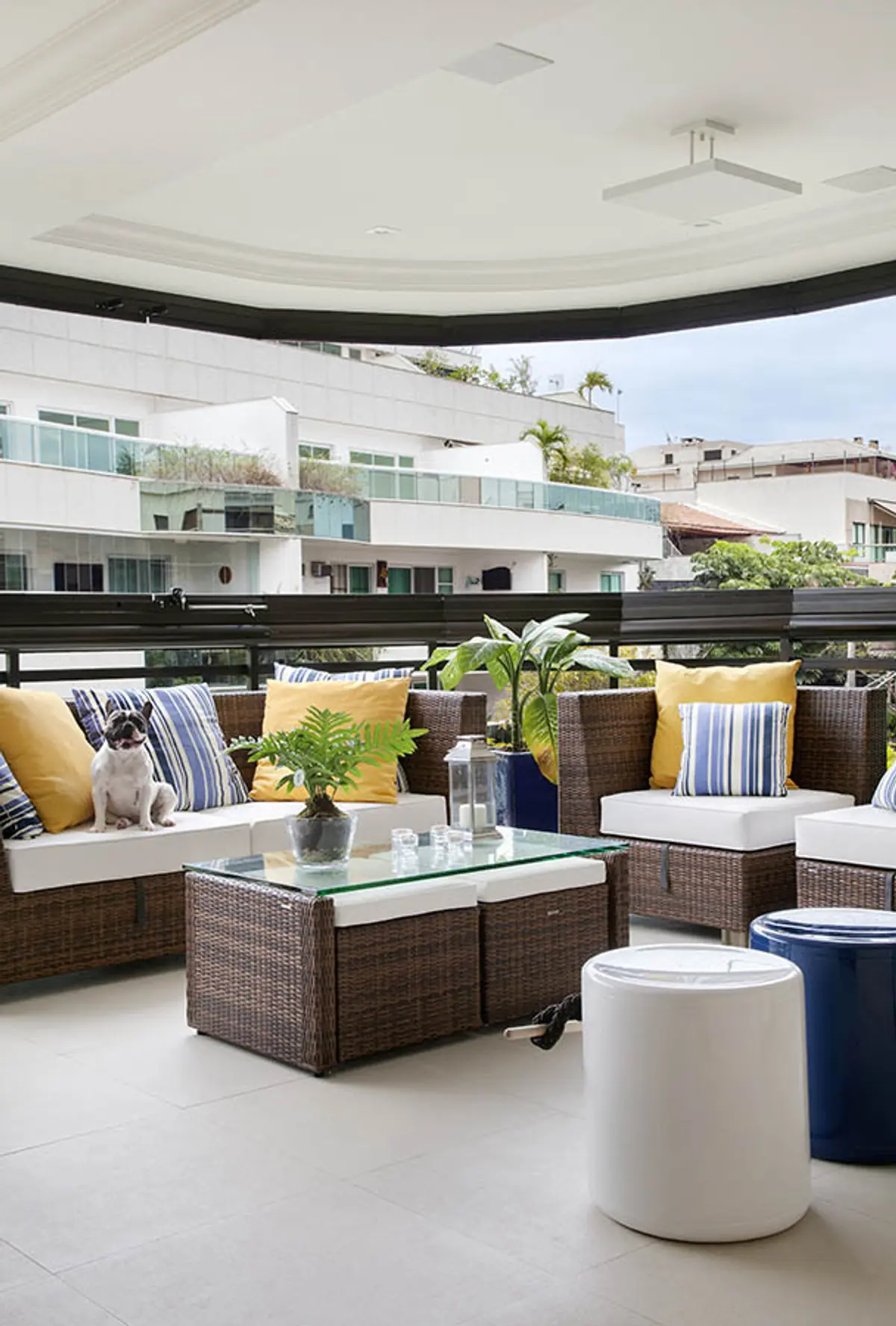 Terraza moderna con muebles de ratán, cojines coloridos y vista urbana — proyecto Apartamento Recreio, por Amanda Miranda