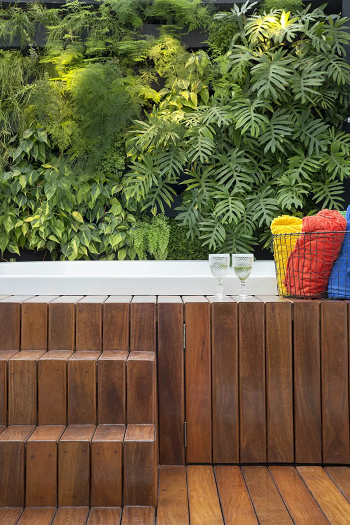 Área de piscina exterior con jardín vertical exuberante y deck de madera — proyecto Cobertura Arquiteta, por Amanda Miranda