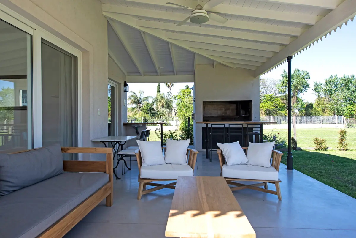 Amplia terraza de madera con pérgola, parrilla y muebles blancos de exterior — proyecto Miradores , por ATO Arquitectos, en Miradores de la Bahia (Bahia Grande Nord