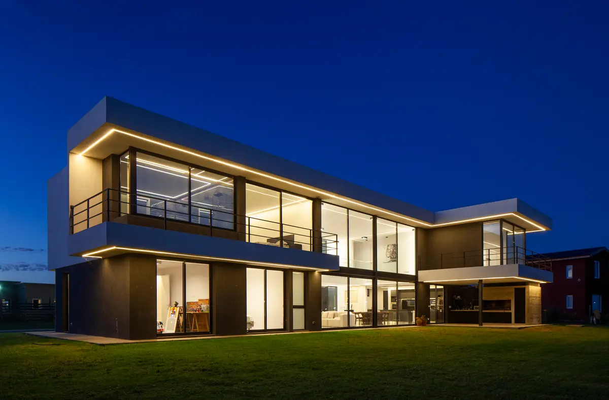 Casa moderna nocturna con grandes ventanales iluminados — proyecto SS A7, Pilar, por ZUID PORT, en Pilar