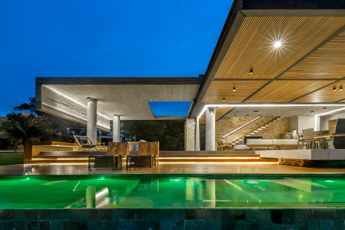 Área externa moderna com piscina infinita e pergolado iluminado — projeto Casa Concreto, por Costaveras Arquitetos