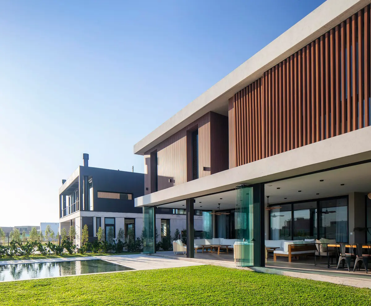 Fachada moderna com piscina e deck de madeira — projeto CASA C313, por A'PRIMA - Arquitectura Sustentable, em Provincia de Buenos Aires