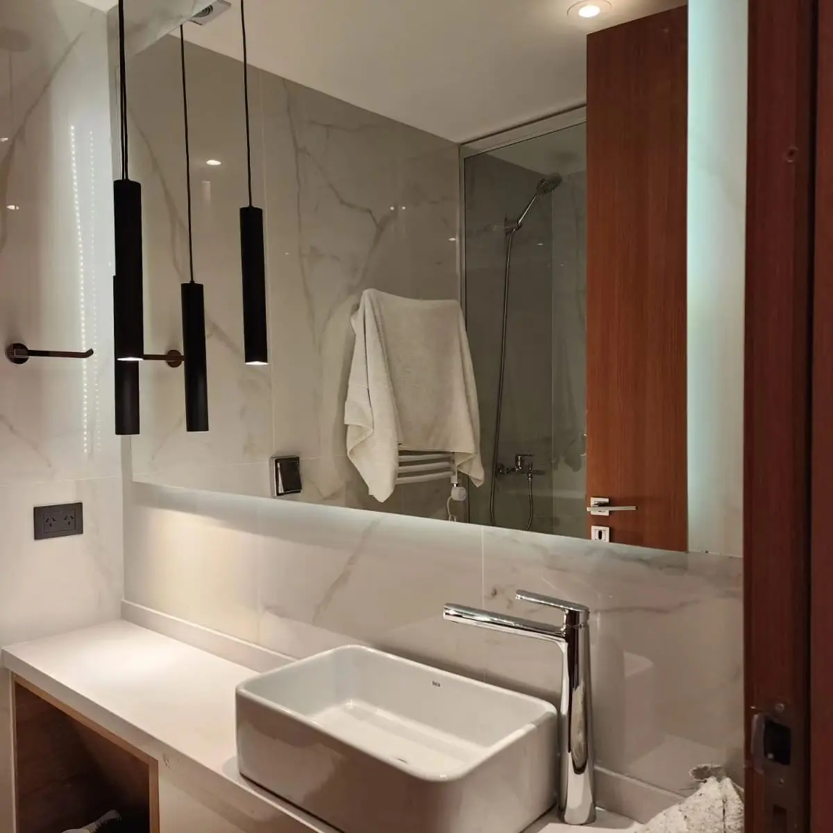 Baño moderno con revestimientos de mármol y grifería negra — proyecto Espejo con bastidor y led, por Cristalcenter, en Recoleta