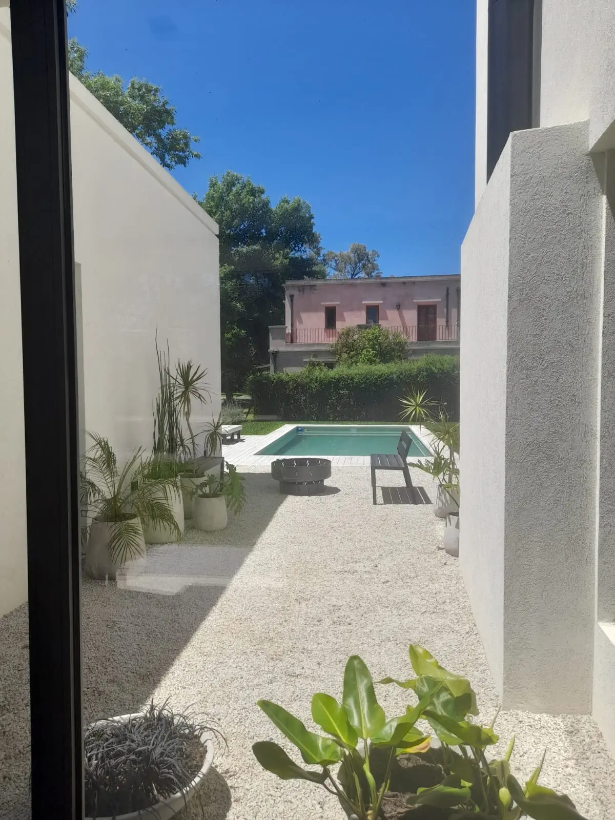 Patio moderno con pileta, jardín de grava y arquitectura blanca — proyecto El 54, por Valeria Damiani Arquitecta, en Pilar