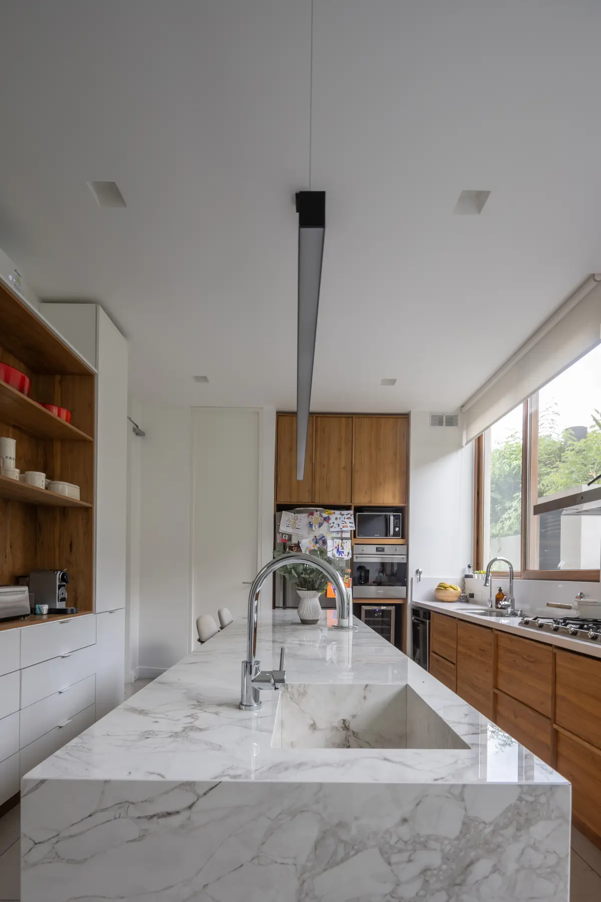 Cocina moderna con isla de mármol y muebles de madera — proyecto CASA OrAz, por Alfredo Orfila arquitectura, en San Isidro