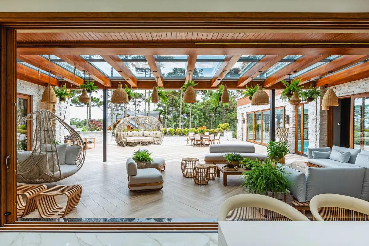 Terraço semiaberto com teto de pérgola de madeira e móveis de rattan — projeto Projeto Destaque Club&Casa, por OKA ARQUITETURA