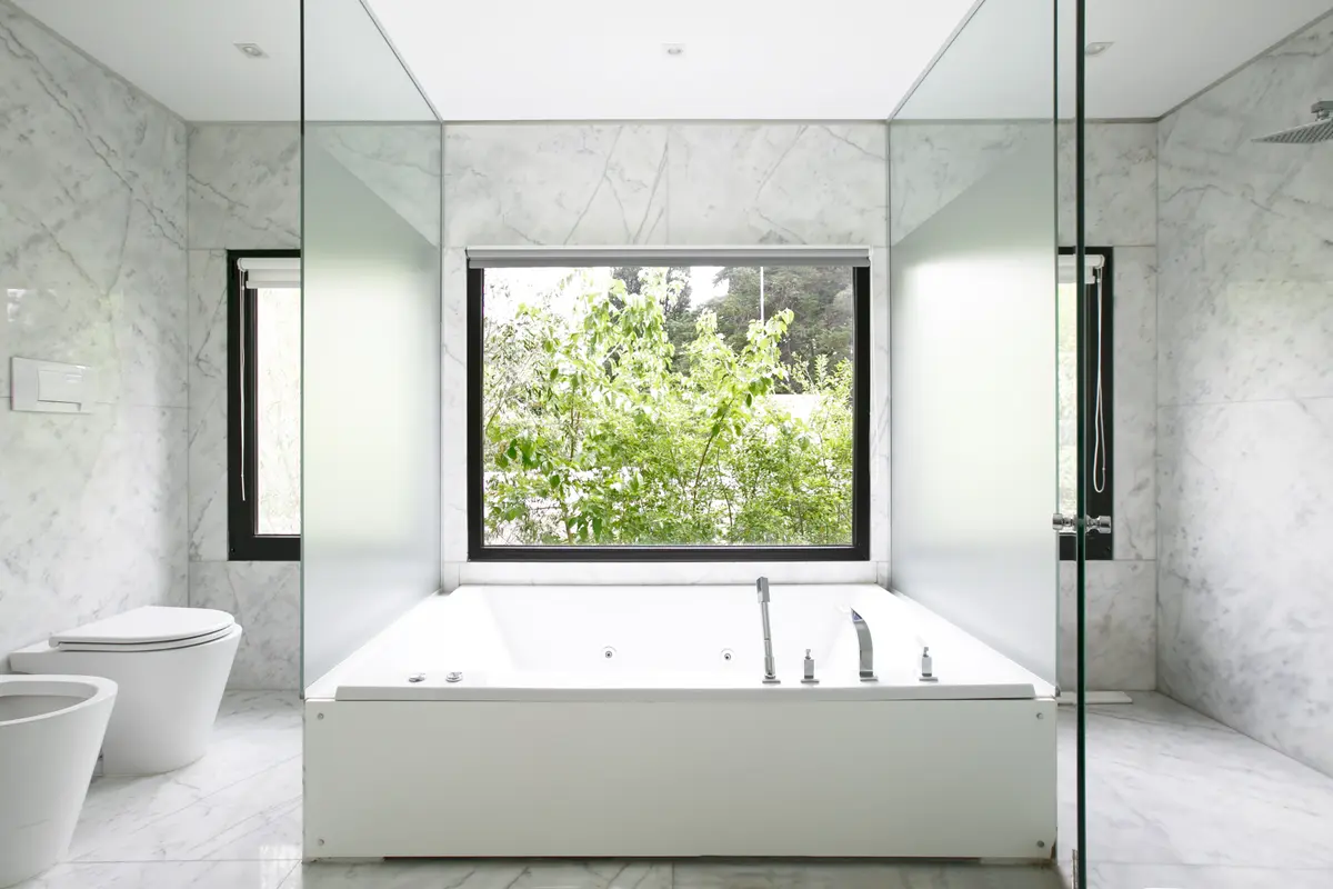 Banheiro moderno com banheira freestanding e grande janela para o exterior — projeto Casa La Chacra, por Clara Chediack