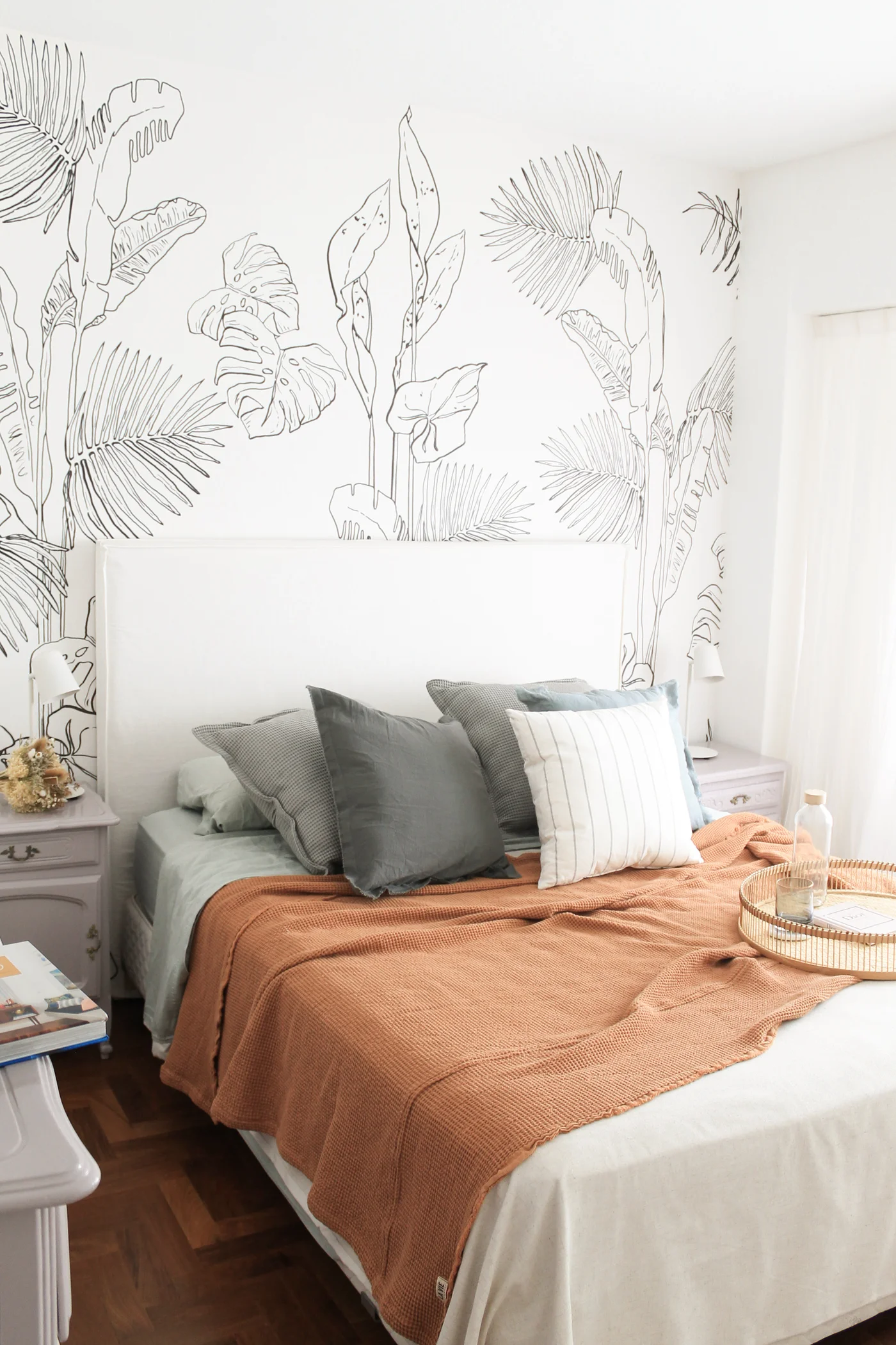 Dormitorio con papel mural botánico y manta terracota