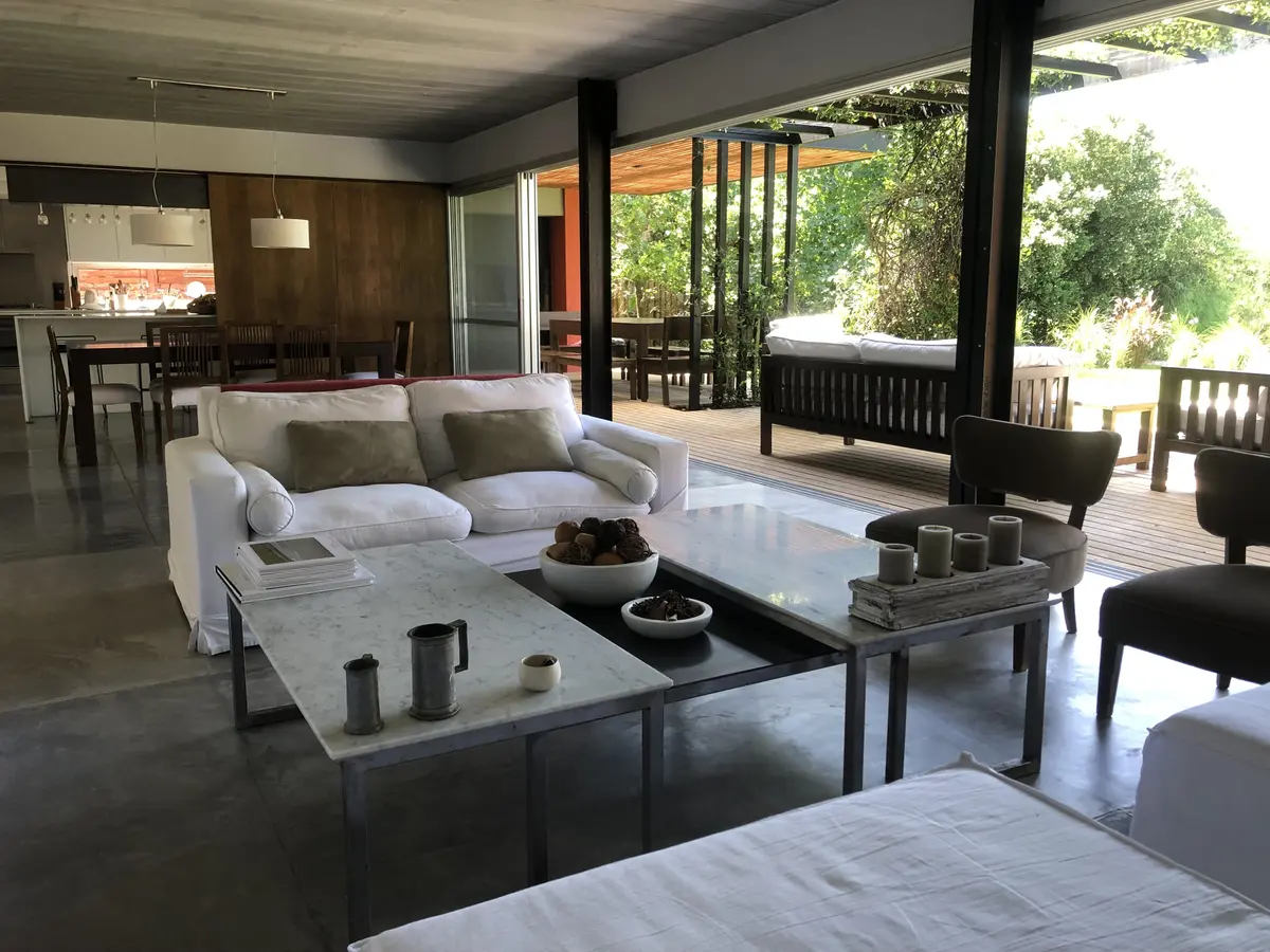 Living moderno con hormigón visto y grandes ventanales al bosque — proyecto MLS3 - Casa en Santa Bárbara, por MLS Estudio, en Benavidez