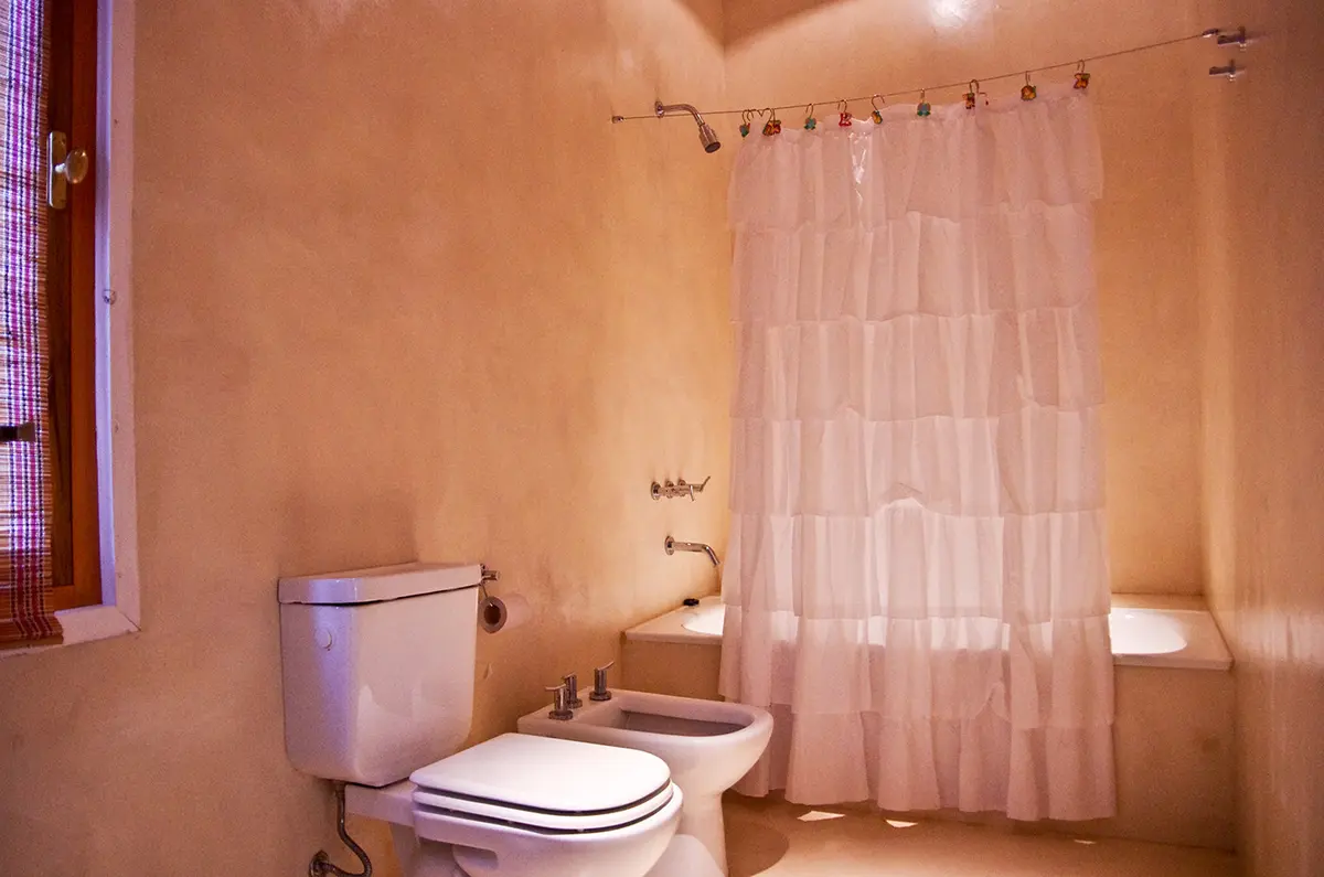 baño de estilo mediterráneo con paredes curvas y cortina blanca — proyecto Chacra Pilará, por Mazzinghi Sanchez, en Pilará