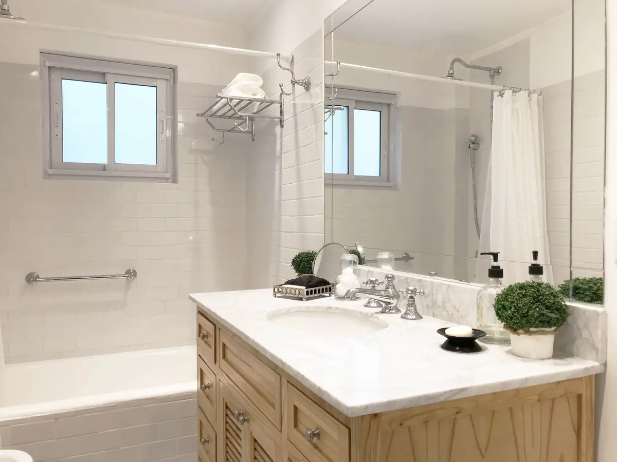 Baño moderno con mueble de madera tallada y mármol — proyecto Obra Alberdi, por Estudio Nicolás Pierry, en CABA