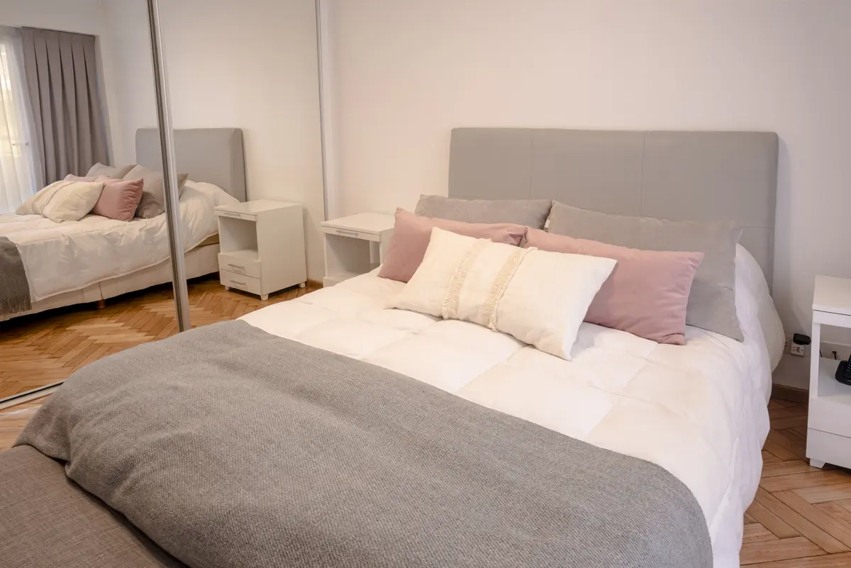 Dormitorio moderno con cama grande y espejo de cuerpo entero — proyecto Austria, por ST Arquitectas, en CABA