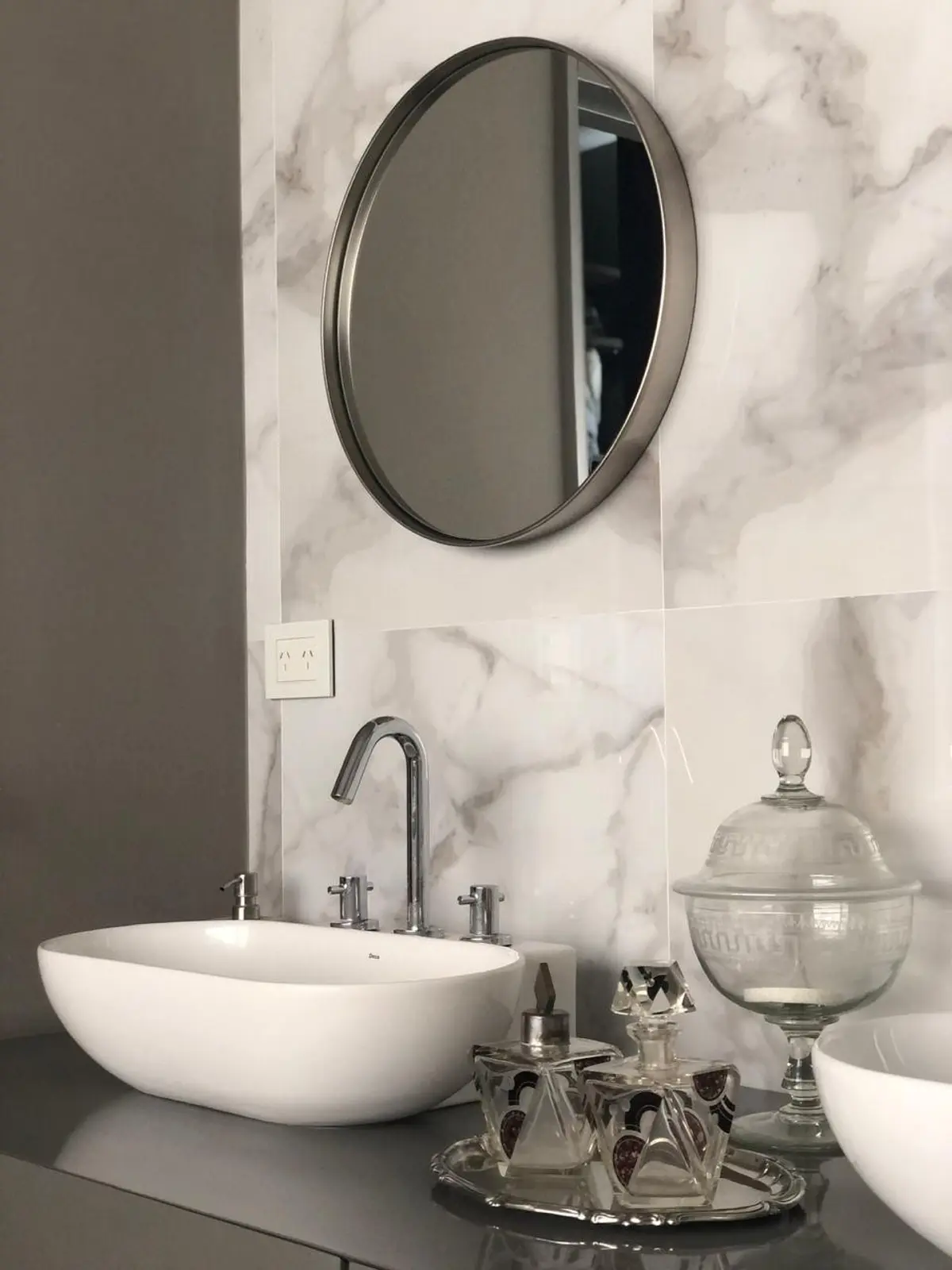Baño moderno con lavabo ovalado blanco, espejo redondo y detalles de mármol — proyecto Casa Nordelta, por Etude Interiorismo, en Nordelta