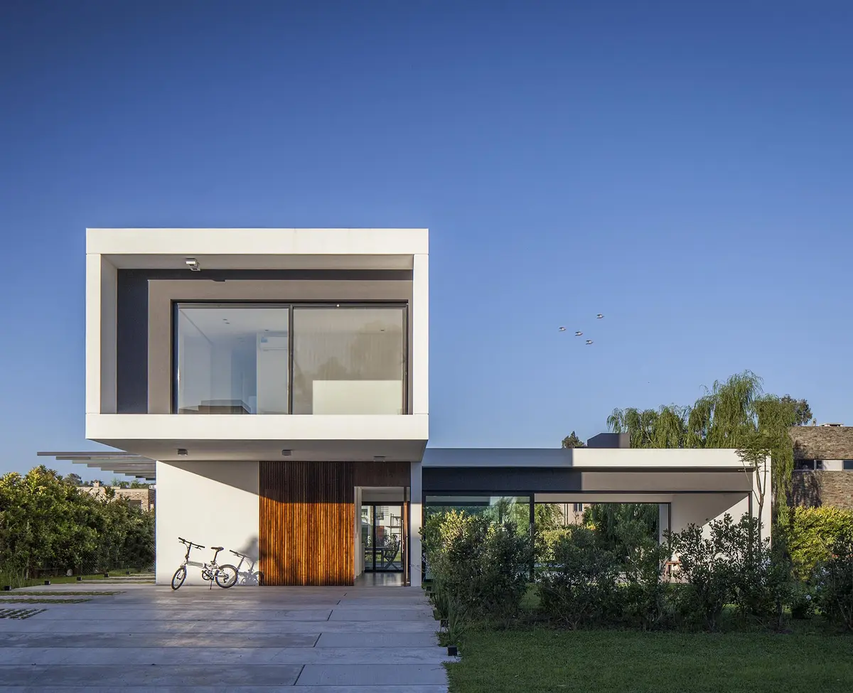 Fachada moderna branca com volume superior em balanço e detalhes em madeira — projeto CASA S2, por GMARQ
