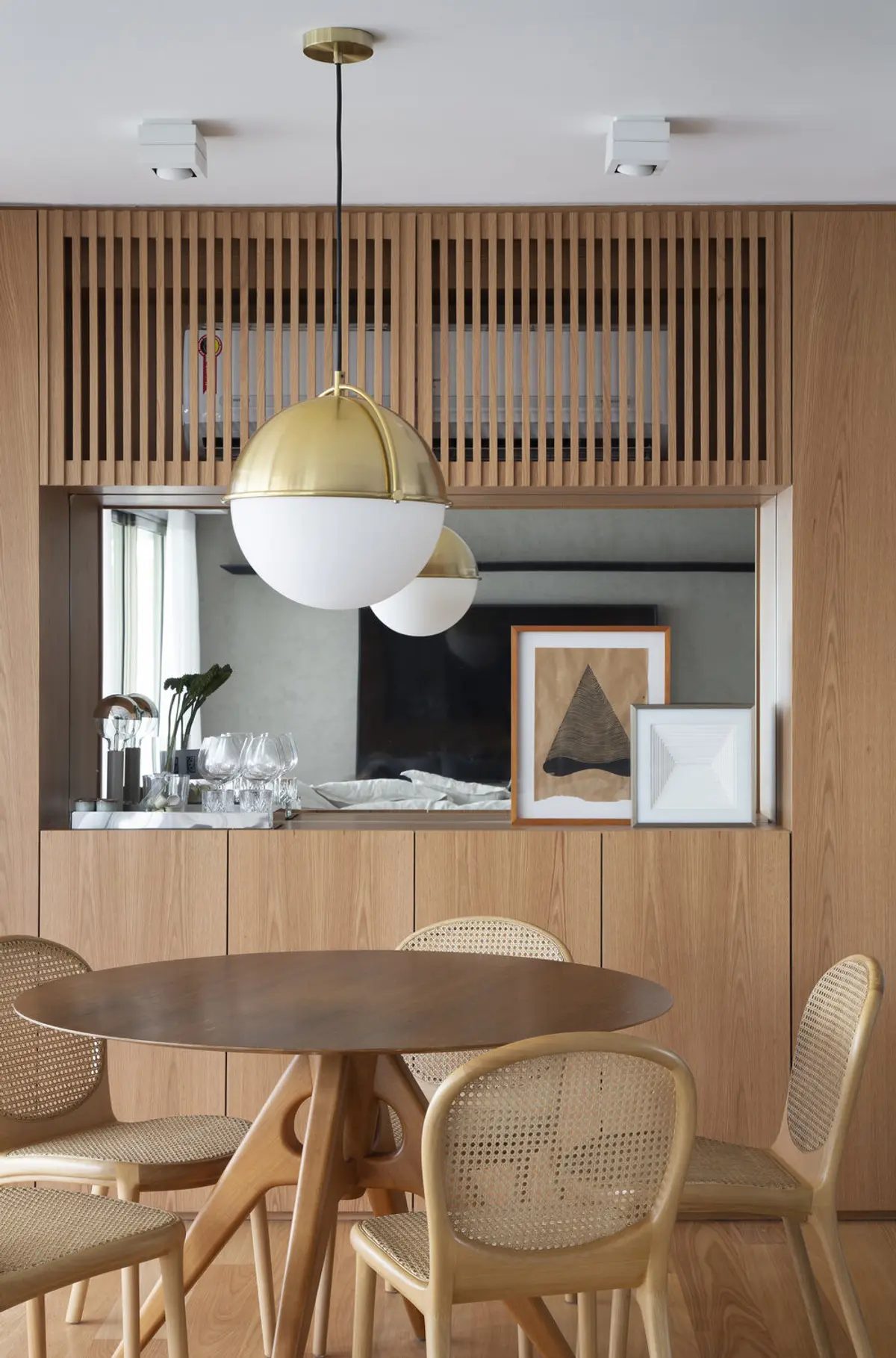 Comedor con mesa redonda, sillas ratán y luminaria dorada colgante — proyecto JG House, por Studio Ro-ca
