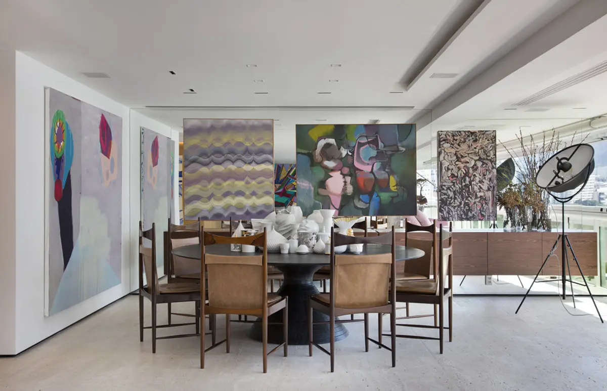 Comedor moderno con mesa redonda y obras de arte colgadas — proyecto RM House, por Studio Ro-ca
