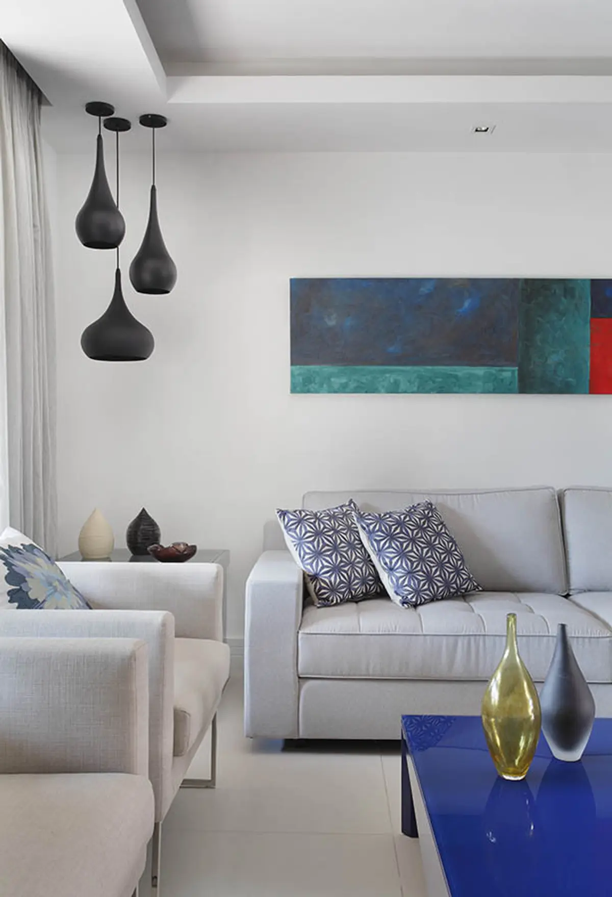 living moderno con sofá gris, lámparas colgantes negras y cuadro abstracto — proyecto Casa Barra ED, por Amanda Miranda