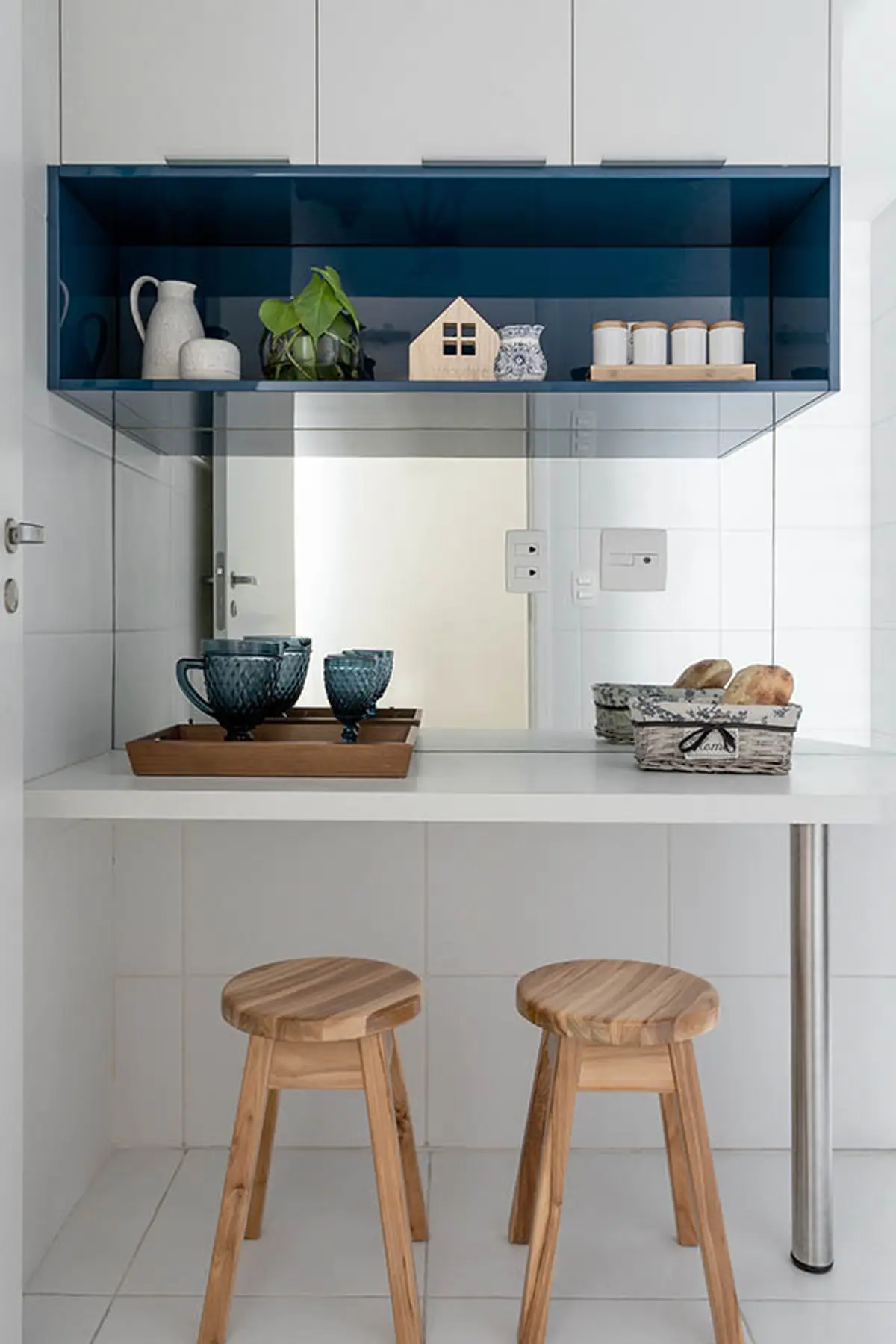 Cocina minimalista blanca con isla, banquetas de madera y estantería azul — proyecto Apartamento Nóbrega, por Amanda Miranda
