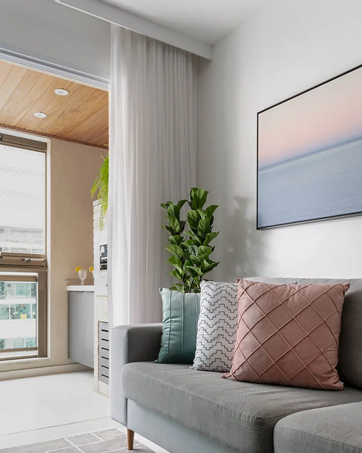 Living moderno con sofa gris, plantas y ventanal luminoso — proyecto Apartamento Nóbrega, por Amanda Miranda