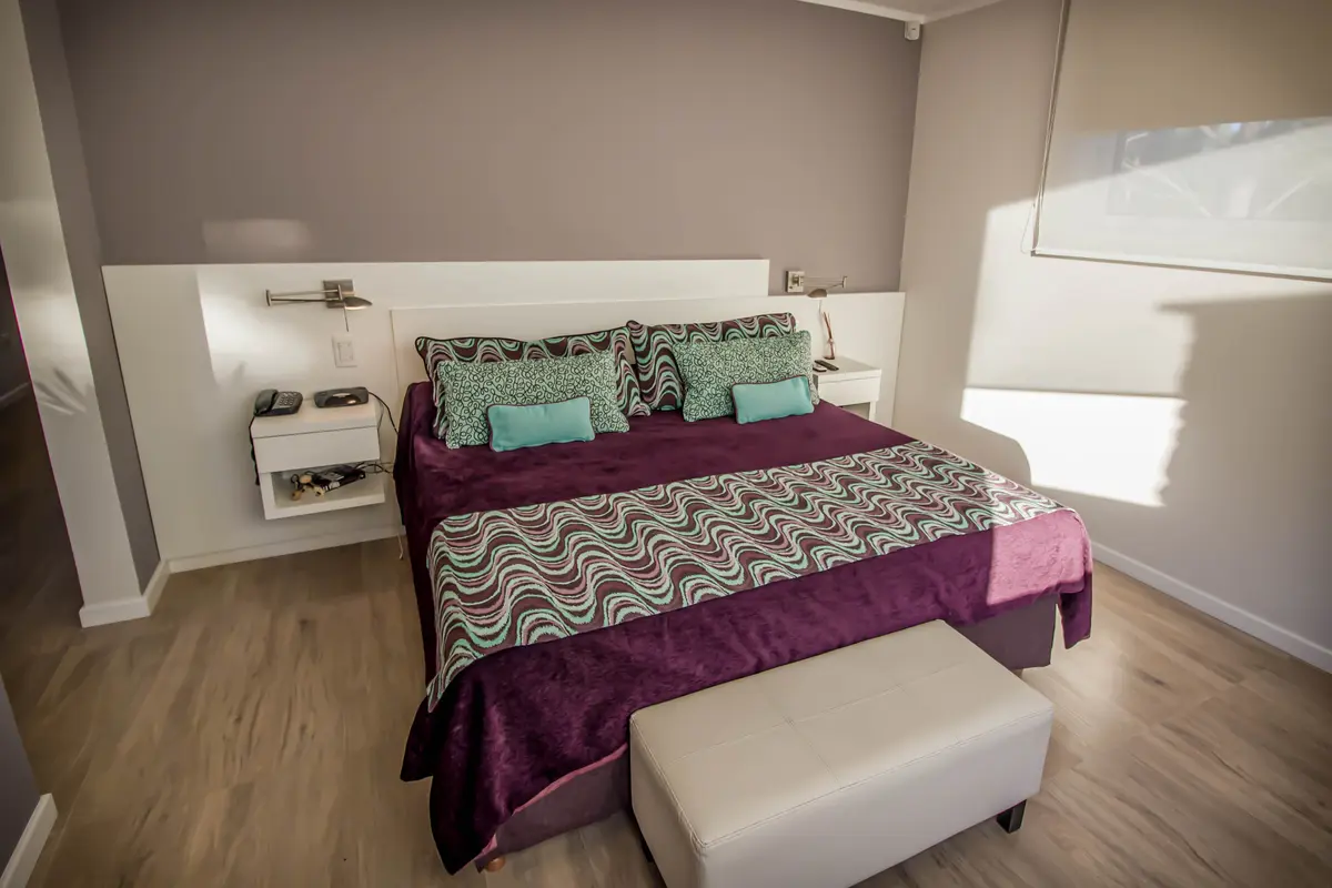 quarto moderno com parede painelada e cama king — projeto Vivienda Unifamiliar en Pinamar, por Estudio Schifano, em Pinamar