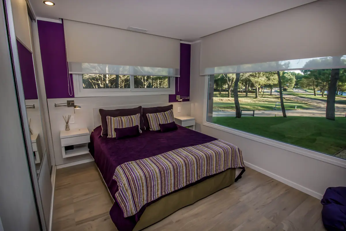 Quarto moderno com vista para a floresta e detalhes em roxo — projeto Vivienda Unifamiliar en Pinamar, por Estudio Schifano, em Pinamar