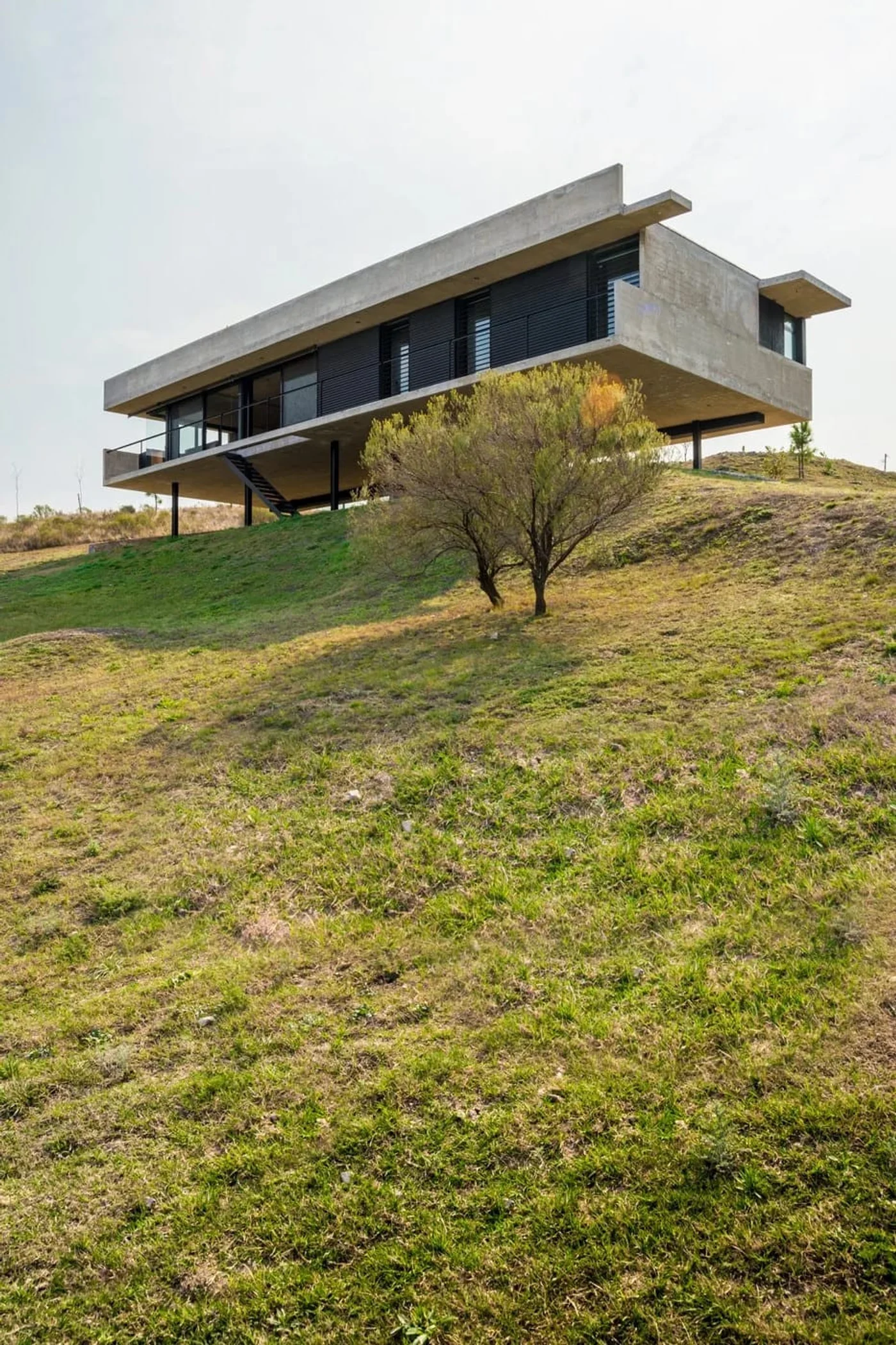Casa moderna con estructura voladiza de hormigón a la vista en ladera.