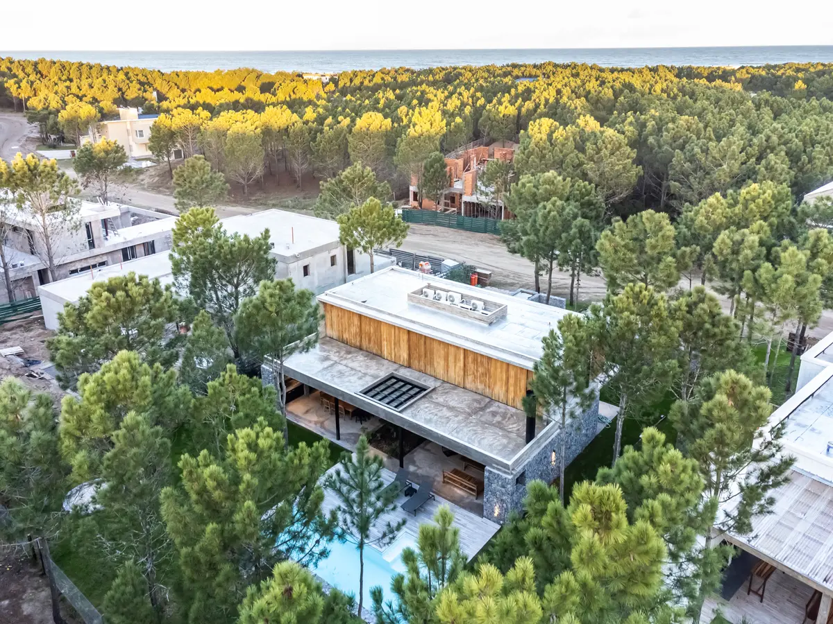 Fachada de casa moderna em floresta de pinheiros com piscina — projeto casa la huella, por Guerrero Arquitectos, em Pinamar