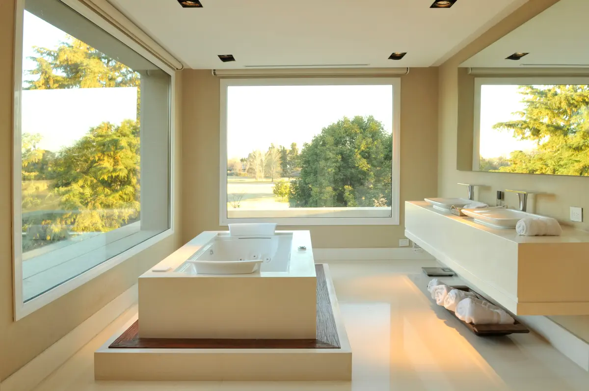 Banheiro moderno com janelas amplas e banheira de imersão com vista para o verde — projeto Pingüinos, por Estudio Consuelo Saravia