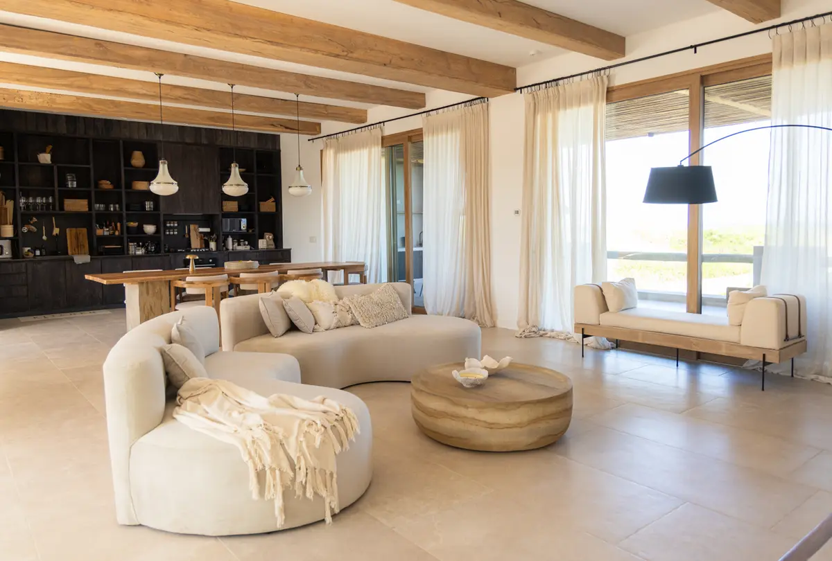 Living moderno con vigas de madera y sofá curvo — proyecto El Refugio, por Grupo Pauta Arquitectura, en Pinamar