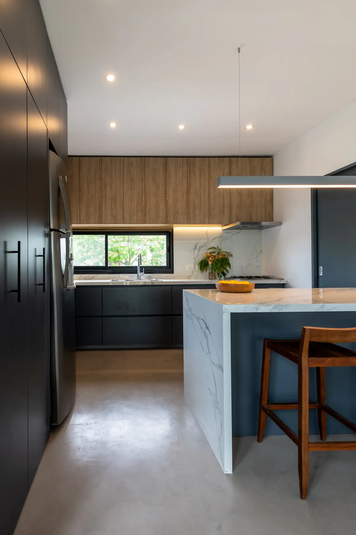 Cocina moderna con isla y barra de cascada, gabinetes de madera oscura — proyecto Santa Isabel - Andrea Gonzalez, por ABEJA CONCEPT, en Nordelta