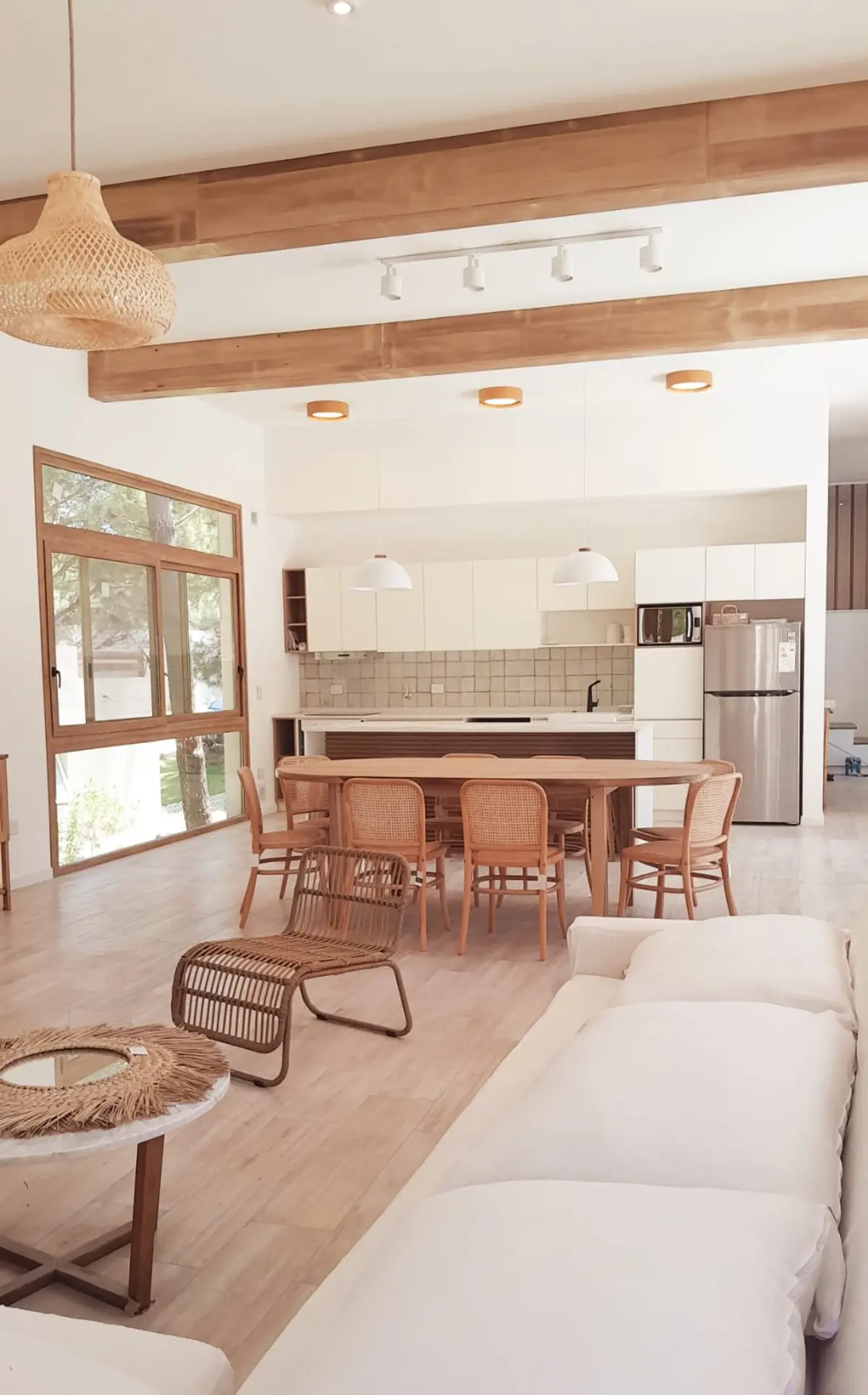 Cozinha e sala integradas com vigas de madeira e muita luz — projeto Casa NF, por TAVA Coop, em Pinamar