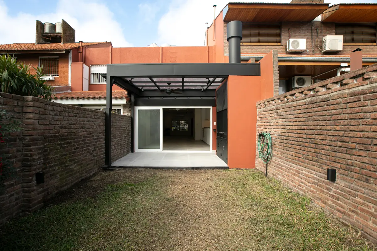 Fachada moderna industrial com pergolado preto e tijolos — projeto Obra Martinez A, por Arq. Lourdes Yarade Saravia, em Martínez