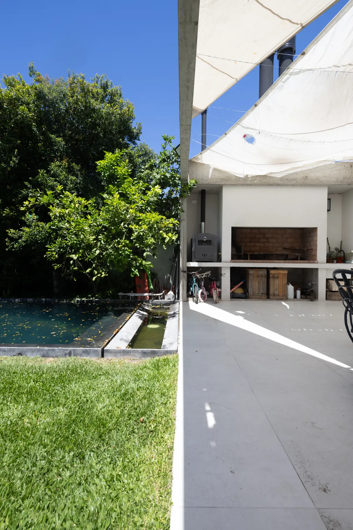 espacio exterior moderno con piscina, parrilla y toldo de tela — proyecto CASA OrBa, por Alfredo Orfila arquitectura, en San Isidro