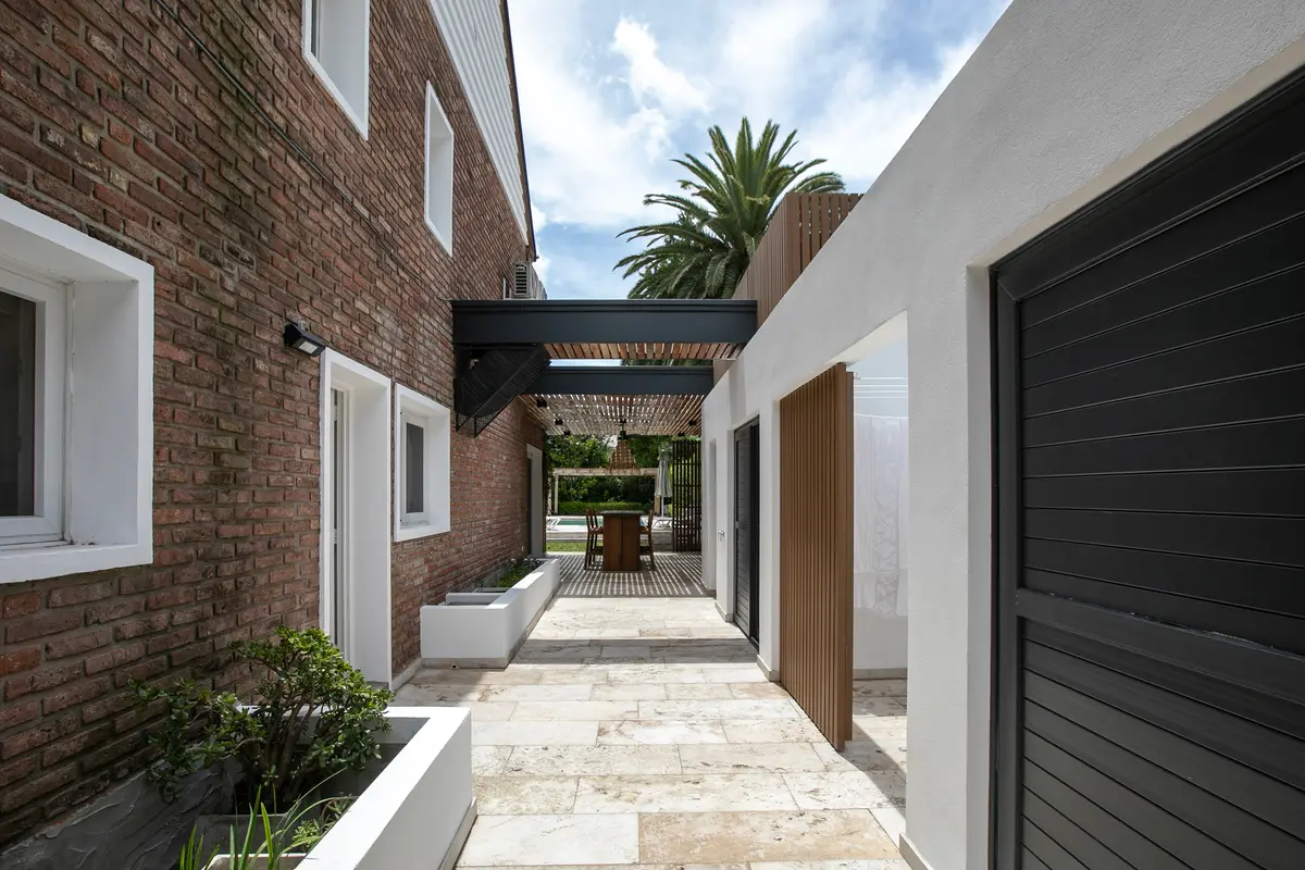 fachada de casa moderna con ladrillos y pérgola — proyecto Obra La Posta, por Arq. Lourdes Yarade Saravia, en Pilar