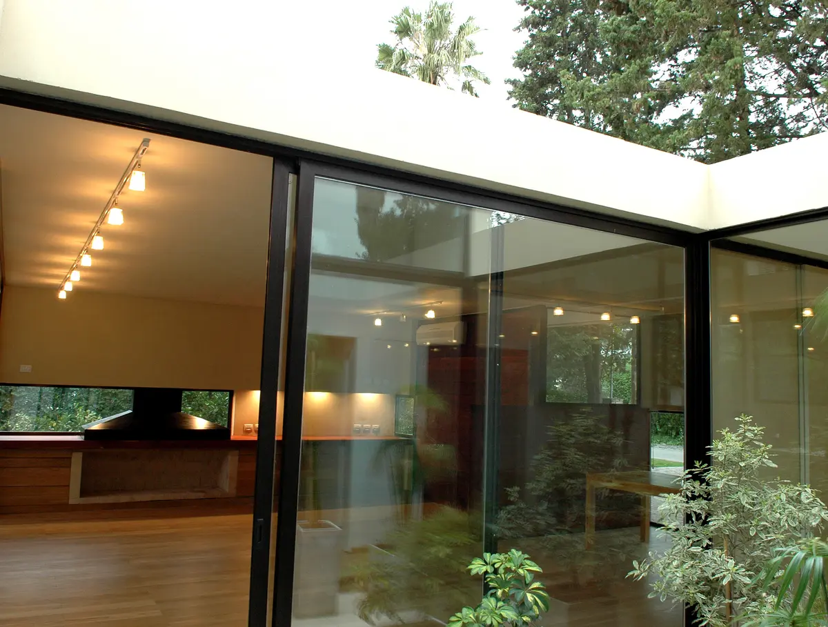 Galería moderna con ventanales amplios, piso de madera y techo retráctil — proyecto Casa en Pilar, por Luciano Kruk, en Pilar