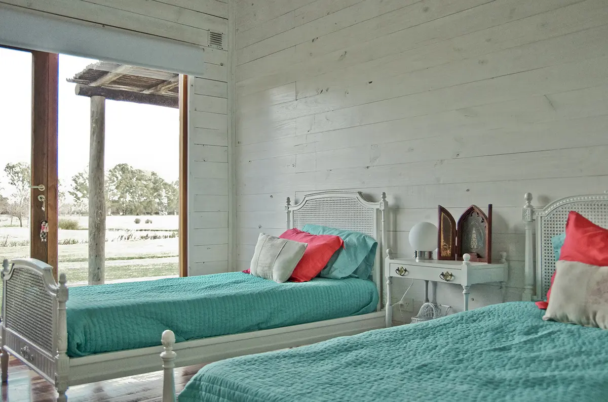 dormitorio rústico con dos camas gemelas y vista al campo — proyecto Chacra Pilará, por Mazzinghi Sanchez, en Pilará