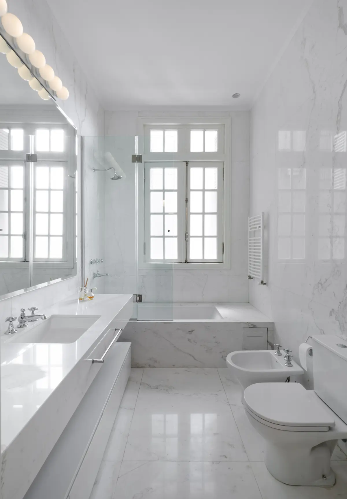 Banheiro moderno minimalista com mármore branco e janelas amplas — projeto Dpto AY, por Estudio Dado, em Recoleta