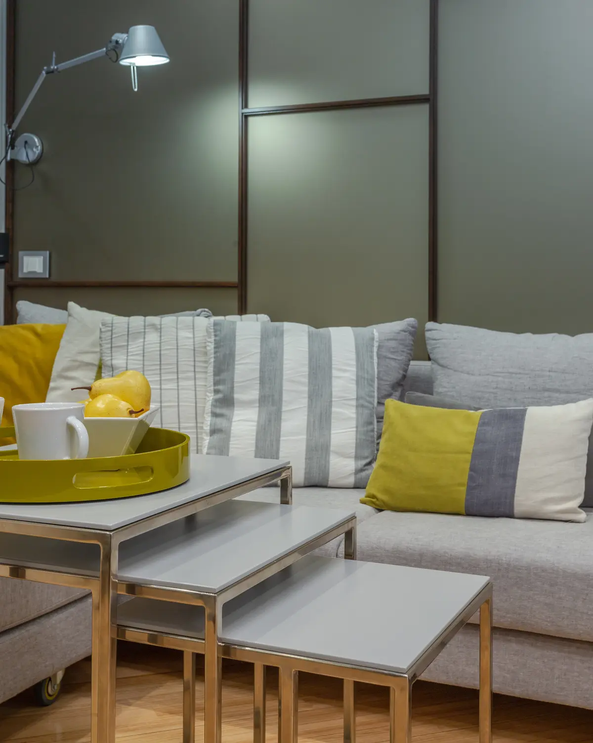 Sala de estar moderna com sofá cinza, mesas aninhadas e luminária de parede — projeto Piso en Belgrano III, por Gutman+Lehrer Arquitectas, em Belgrano