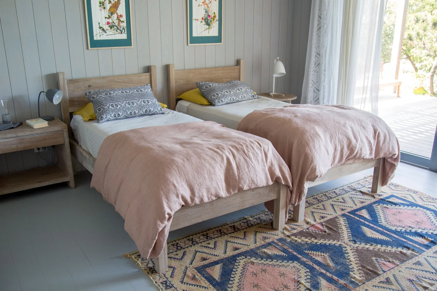 dormitorio con dos camas, paredes de madera y alfombra geométrica.