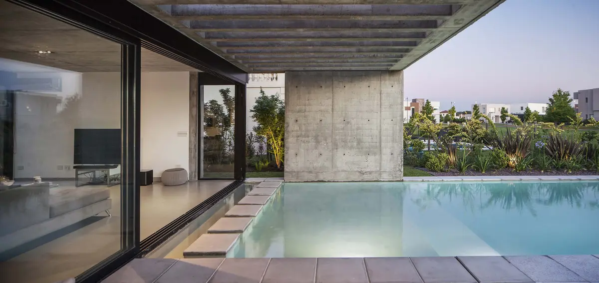 Casa moderna con pileta exterior y living integrado de hormigón visto — proyecto CASA EH, por GMARQ