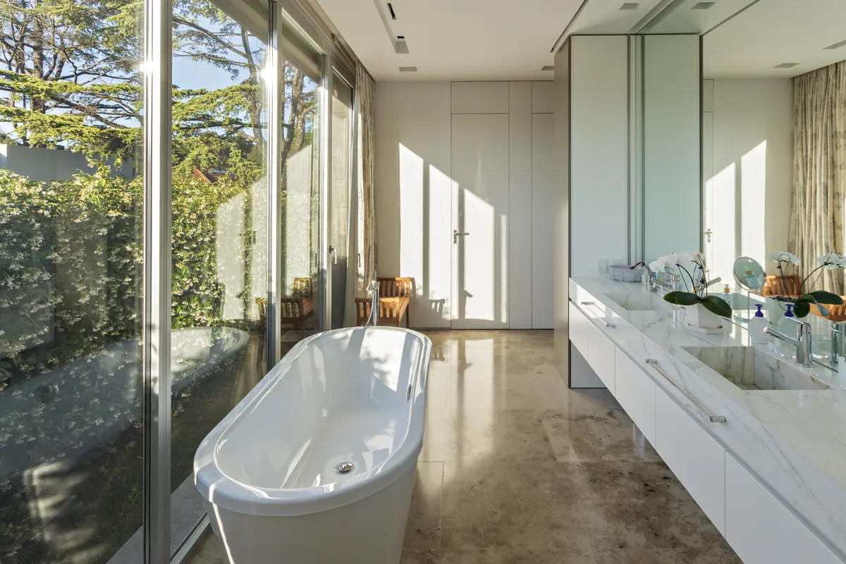 Banheiro moderno com janelas amplas e banheira freestanding, muita luz natural — projeto Casa ML, por Alric Galindez Arquitectos