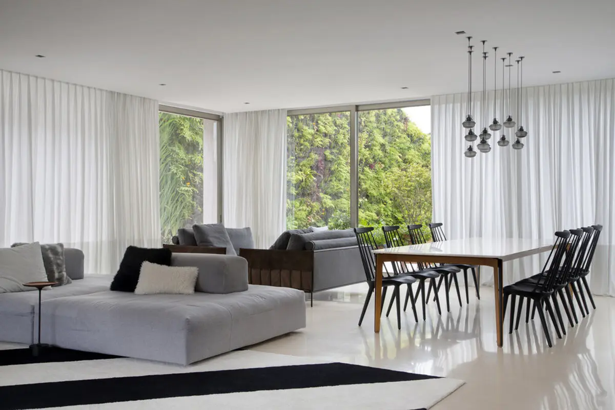 Living minimalista con ventanales, comedor y zona de descanso integrada — proyecto BM House, por Studio Ro-ca