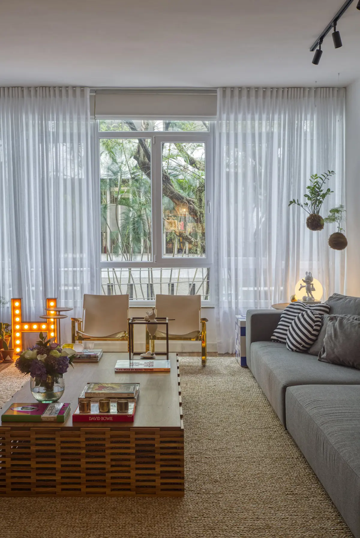 Living contemporáneo con ventanal hacia jardín, sofá gris y sillas de madera — proyecto Hugo Gloss, por Studio Ro-ca