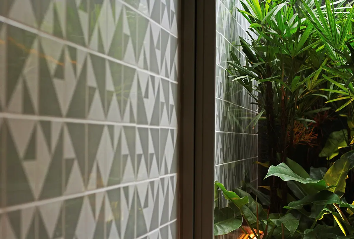 Detalle de pared con patrón geométrico y jardín vertical adentro — proyecto Residência MC, por Gil Fialho