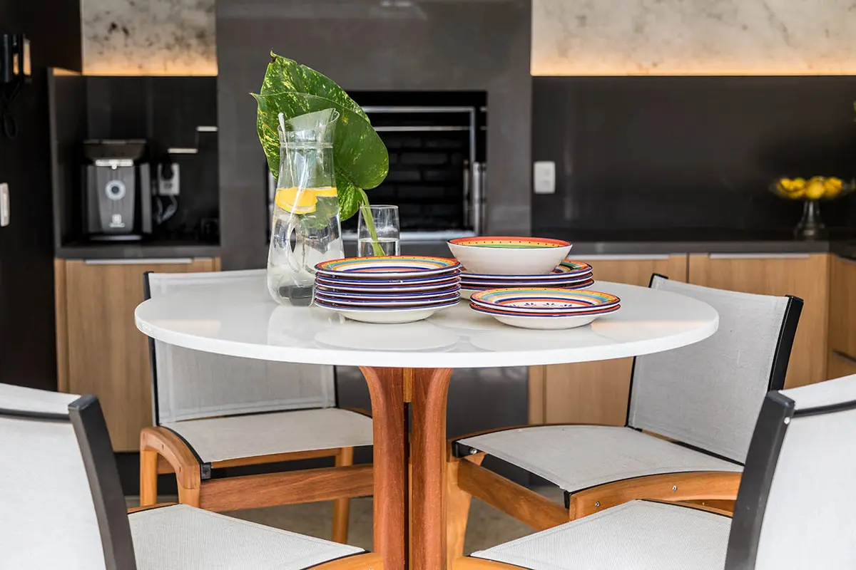 Comedor moderno con mesa redonda blanca y sillas de madera en cocina abierta — proyecto Casa Barra ED, por Amanda Miranda