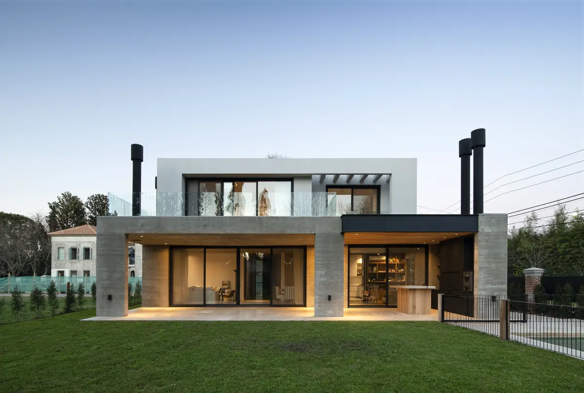Casa moderna de concreto com grandes janelas e jardim verde — projeto Casa Rouco, por Estudio Lak
