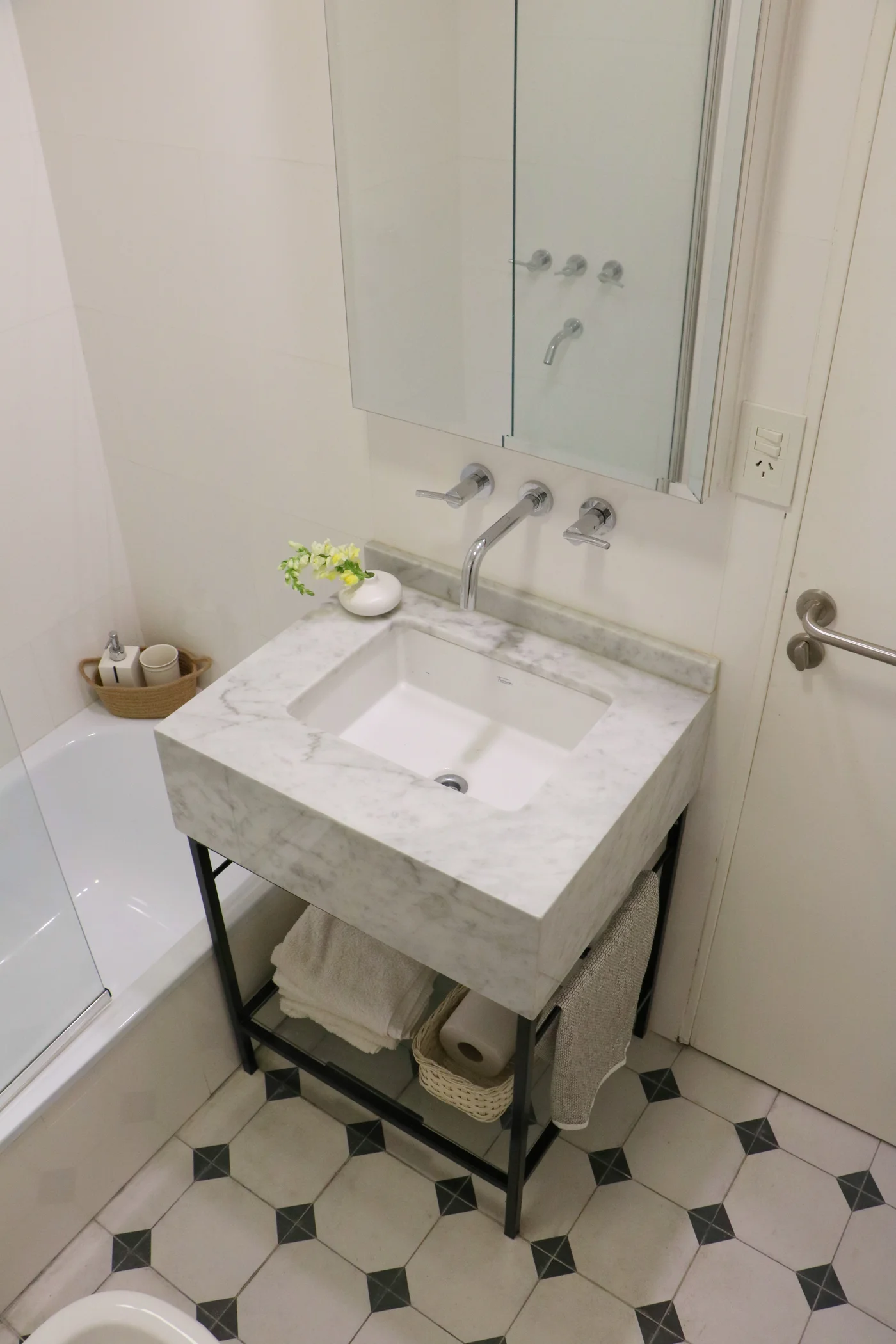 Baño moderno con vanitory de mármol, bacha blanca y grifería cromada.
