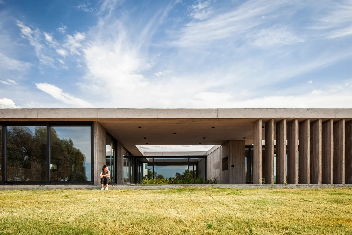 Fachada moderna com pergolado de concreto e grandes janelas — projeto Casa JUMP, por V2 Arquitectos, em City Bell